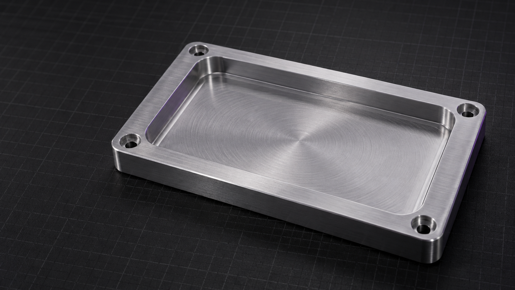 An illustrative aluminum part with a machined pocket and four mounting holes on a dark workbench.